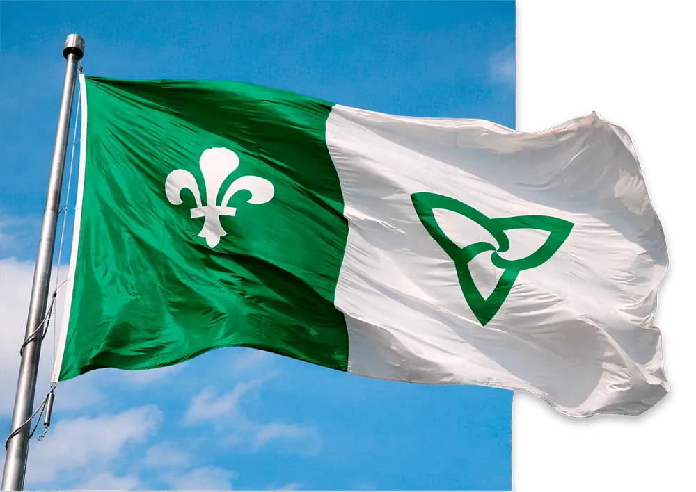Le drapeau franco-ontarien flotte dans un ciel bleu.