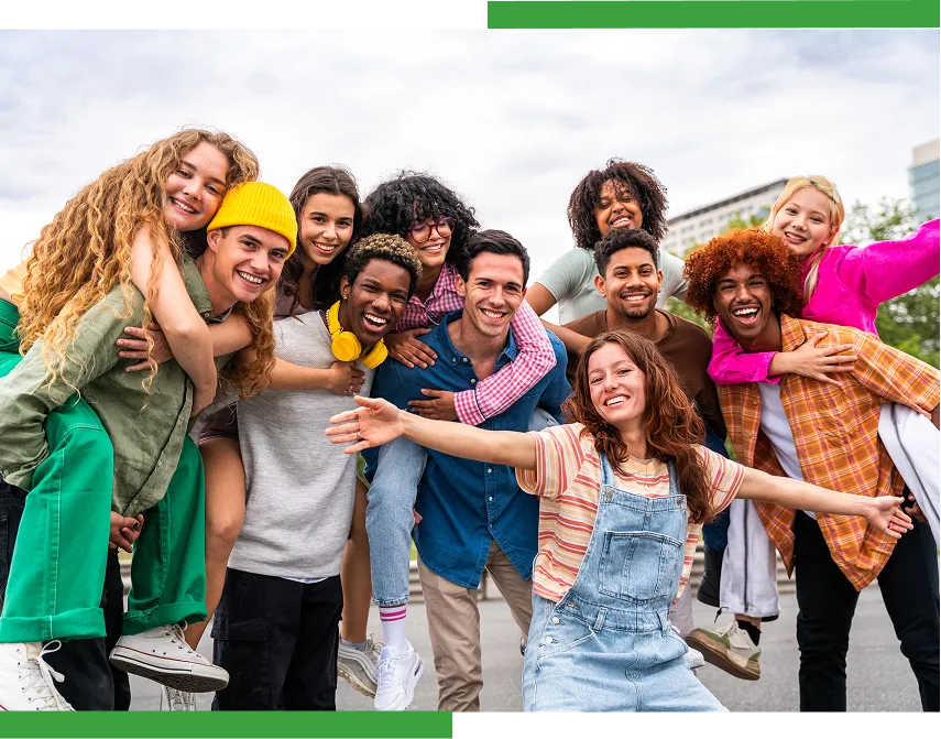 Un groupe de dix jeunes d’origines diverses sourit avec enthousiasme et se prend par l’épaule à l'extérieur.